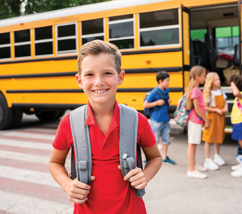 Young child in front of a yellow school bus