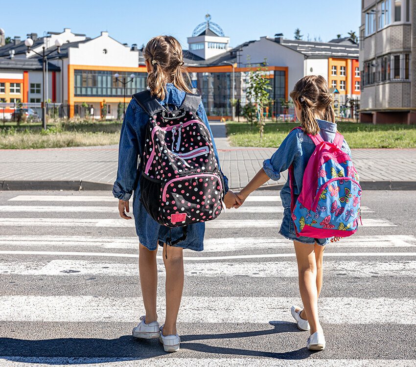 Two children crossing street in crosswalk